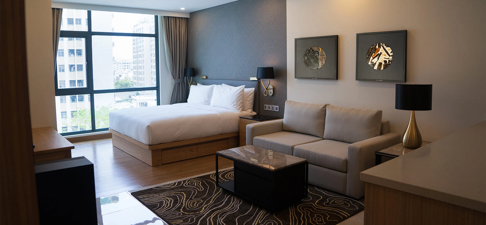 Modernes Hotelzimmer mit einer Couch über der ein Natursteinkunstwerk hängt